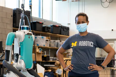 Eva Mungai stands next to a Digit, a bipedal Agility Robotics robot, in her lab.