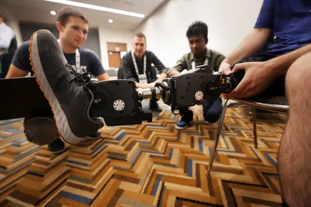 Professor Elliott Rouse, center, speaks with Kevin Best, left, a Robotics PhD, and Senthur Ayyappan, right, who works with Rouse on the Open-Source leg. The leg is being worn by first year Mechanical Engineering PhD student Andrew Seelhoff.