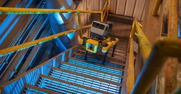 Boston Dynamics Spot robot quadruped walks up industrial staircase.