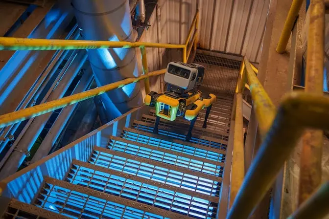 Boston Dynamics Spot robot quadruped walks up industrial staircase.