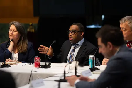 A group at a conference table with a man speaking and gesturing.