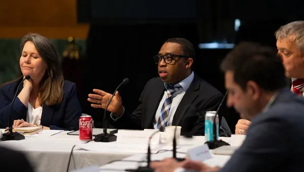 A group at a conference table with a man speaking and gesturing.
