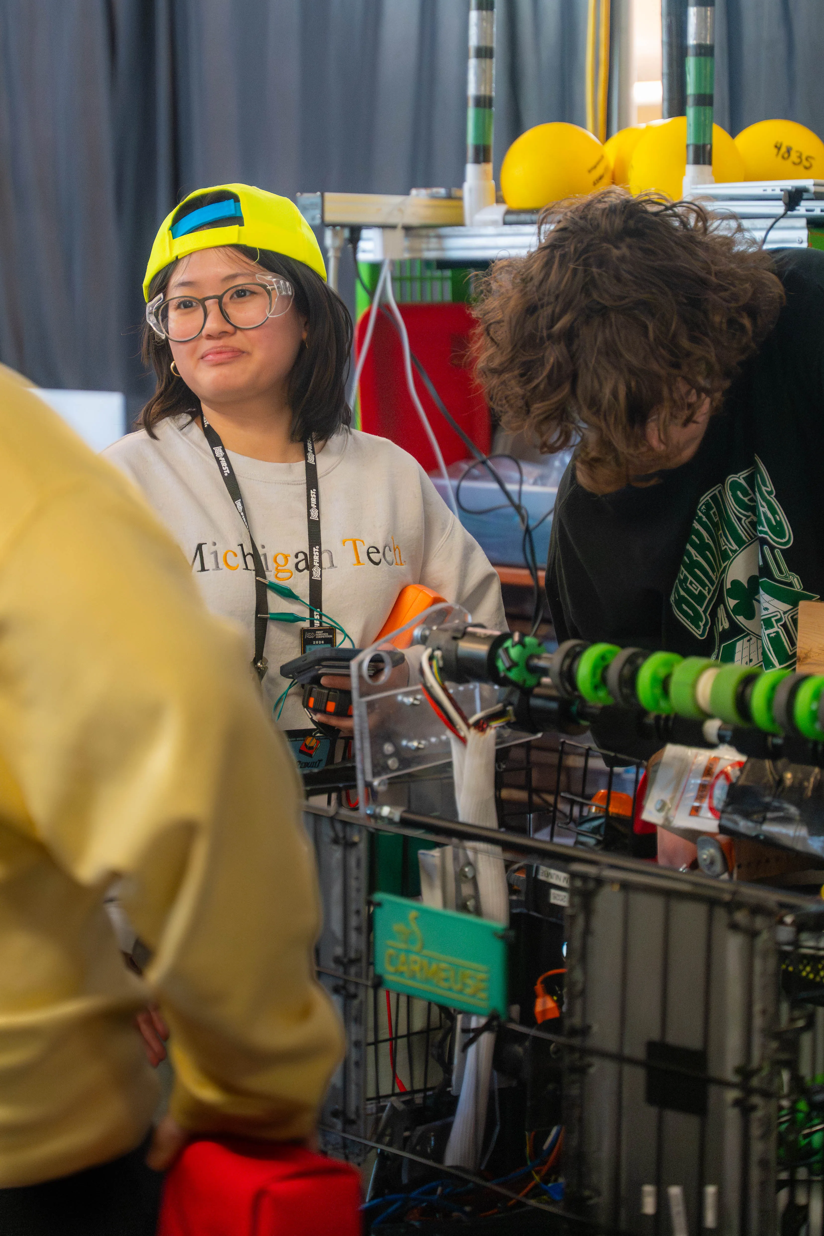 Athena Lieu stands next to a robot and high school teammember at the Escanaba competition.