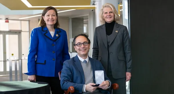 Jason Corso sits in the chair representing the professorship, with Robotics Department chair Dawn Tilbury and Dean Karen Thole behind.