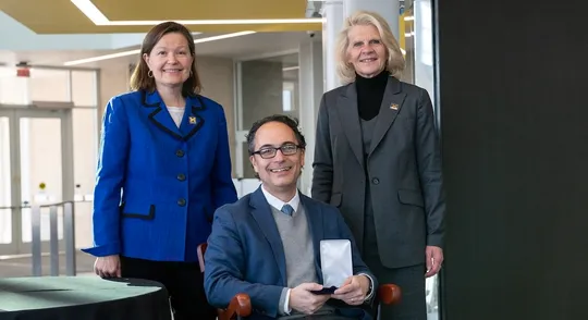 Jason Corso sits in the chair representing the professorship, with Robotics Department chair Dawn Tilbury and Dean Karen Thole behind.
