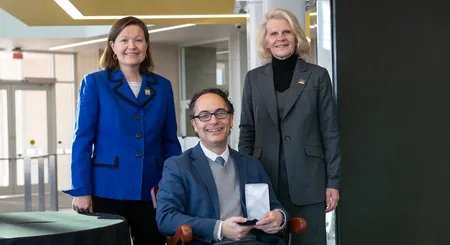 Jason Corso sits in the chair representing the professorship, with Robotics Department chair Dawn Tilbury and Dean Karen Thole behind.