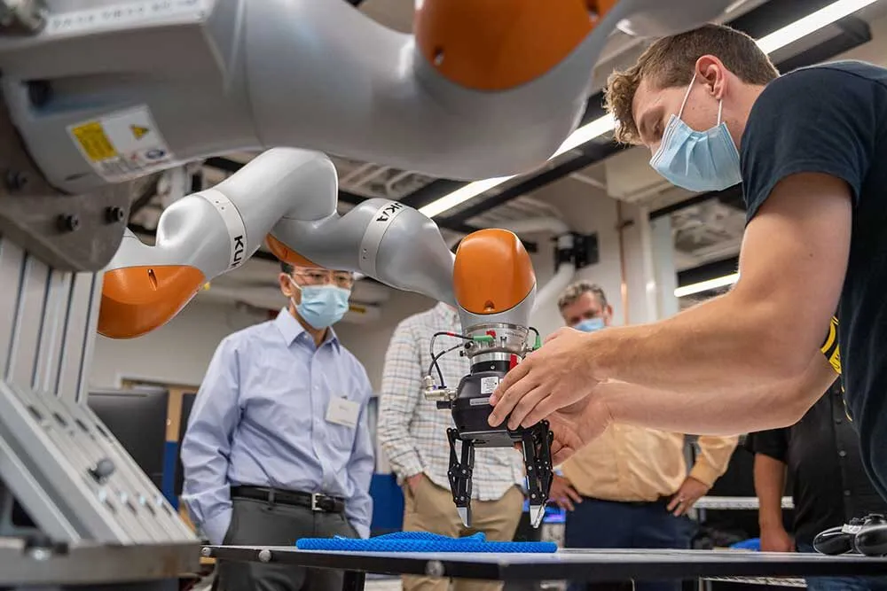 A large industrial robot arm is moved by a researcher to a more exact position.