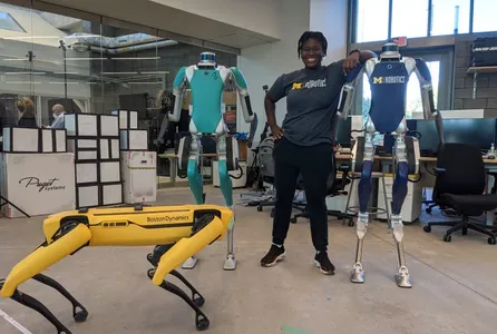 Dr. Ogunbi posing with three robots