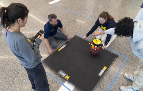 Lecturer and students test an MBot on a balancing board