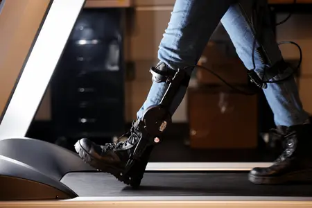 Close-up of a robotic ankle exoskeleton being tested on a treadmill