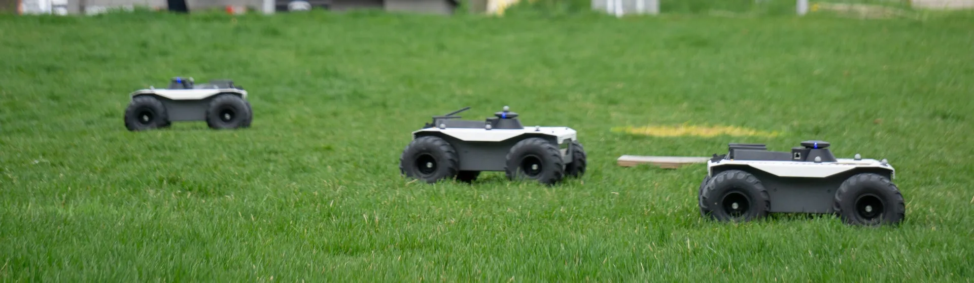 A team of four-wheeled ground robots roll across M-Air.
