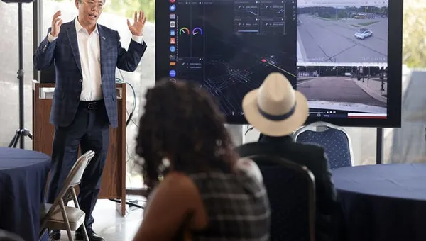 Faculty presenting a slideshow in front of a group of visitors.