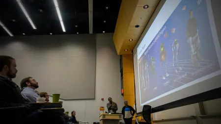 An audience looks on at a robotics presentation.