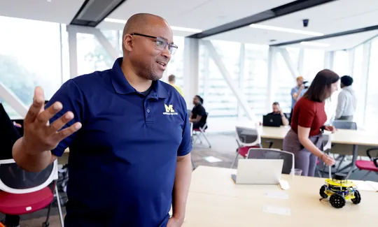 Chad Jenkins speaks with attendees at the Distributed Teaching Collaborative Summer Session at the Ford Motor Company Robotics Building.