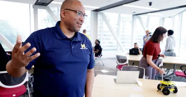 Chad Jenkins speaks with attendees at the Distributed Teaching Collaborative Summer Session at the Ford Motor Company Robotics Building.