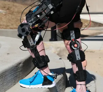 A person wearing a knee exo standing across stairs outside.