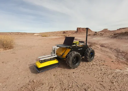 A four-wheel Clearpath Husky robot with a ground penetrating radar attached moves in stark Utah desert.