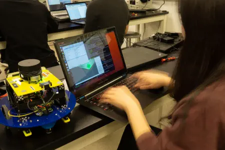 A student programs an MBot mobile robot in a robotics lab