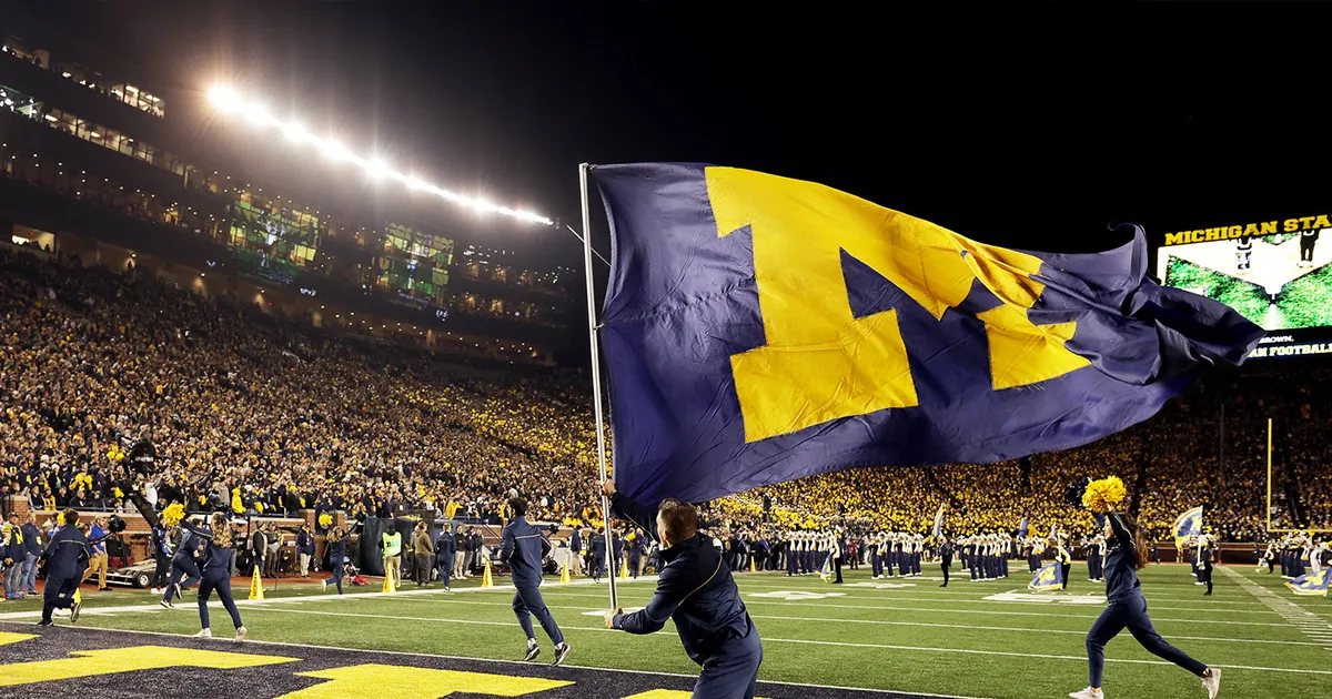 A gigantic U-M flag is waved in the Big House football stadium