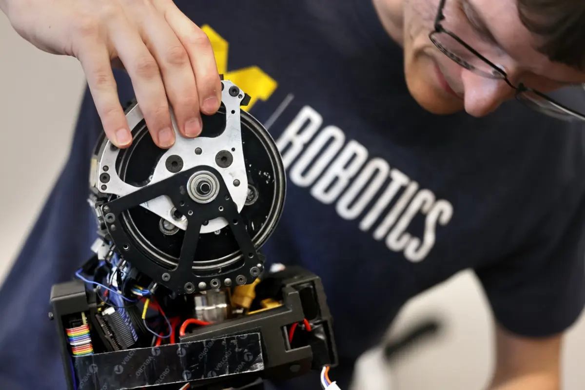 A researcher examines a robotic joint mechanism at the IROS conference