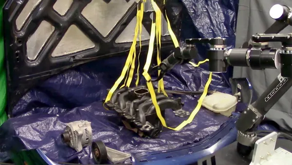 A robot performs the difficult to model task of manipulating straps without tangling them around a mock car engine in the Autonomous Robotic Manipulation Lab.