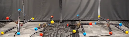 A robot made of three tubes and cables connecting them tumbles across the floor in different arrangements in this composite image.