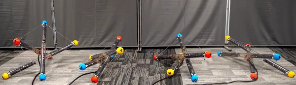 A robot made of three tubes and cables connecting them tumbles across the floor in different arrangements in this composite image.