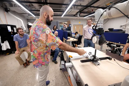 Nima Fazeli in his lab shows visitors a robotic arm equipped with special touch sensors. Photo: Brenda Ahearn/University of Michigan, College of Engineering, Communications and Marketing