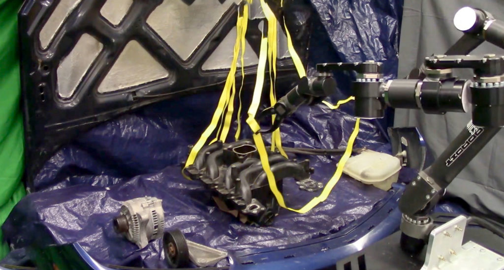 A robot performs the difficult to model task of manipulating straps without tangling them around a mock car engine in the Autonomous Robotic Manipulation Lab.
