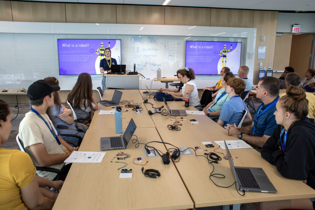 A roboticist presents in front of a group of students and parents during a summer camp activity with Arduinos.